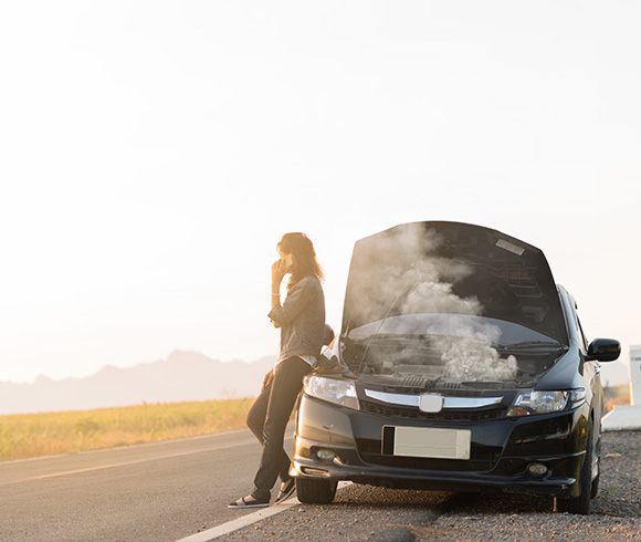 person standing next to a car with smoke coming from the engine on a rural road alone with eight potential issues to consider