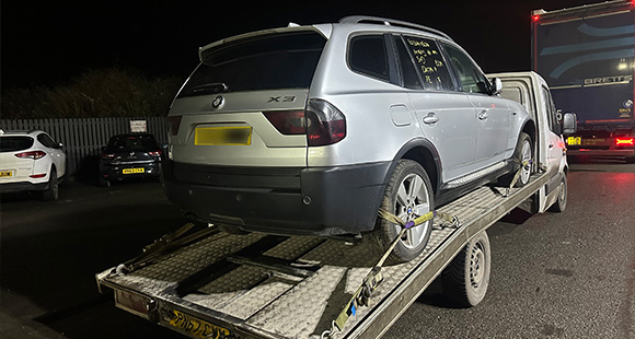 Silver BMW X3 being towed on a flatbed truck at night showcasing vehicle transport and recovery services 3 car towing X3 model