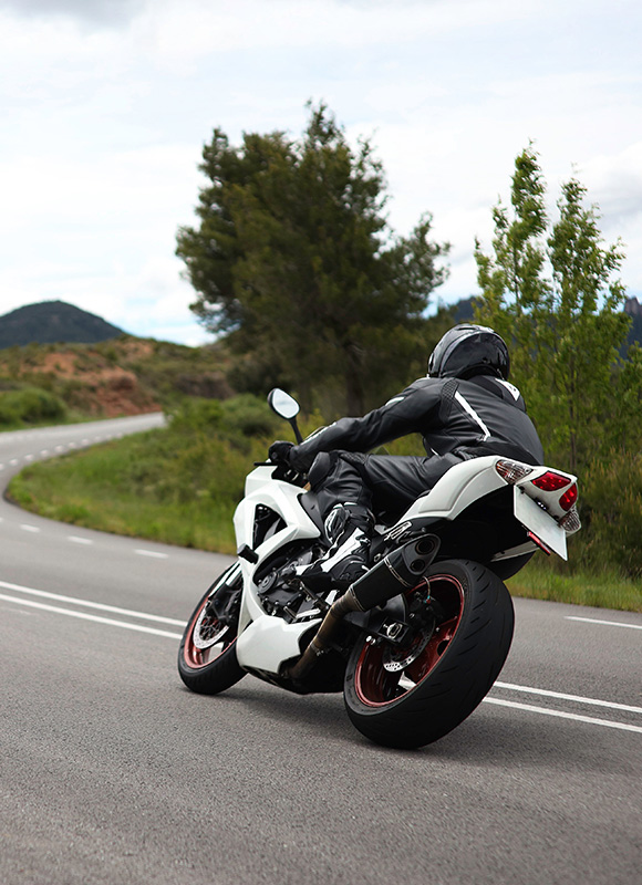 motorcycle rider in black gear on winding road surrounded by greenery showcasing sleek design and speed opportunities for adrenaline seekers with 8 exhilarating turns ahead